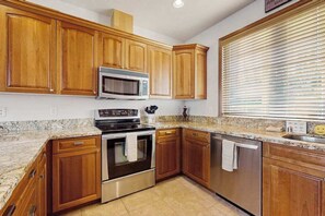 A kitchen with wooden cabinets, stainless steel appliances, and a granite countertop.