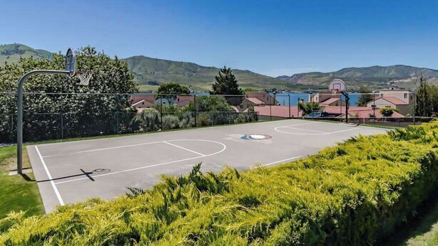 An outdoor basketball court with a clear view of the surrounding residential area and hills in the background. - Charming 2BR Lakefront - Patio - Pool (Chelan)