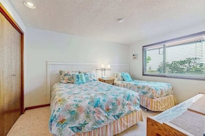 A bedroom with two beds, a window with blinds, a nightstand, and a wooden wardrobe. - Charming 2BR Lakefront - Patio - Pool (Chelan)