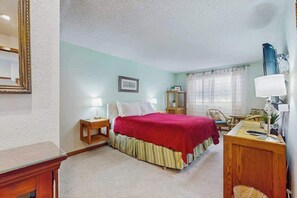 A bedroom with a bed, bedside table, lamp, and a desk with a chair. - Charming 2BR Lakefront - Patio - Pool (Chelan)