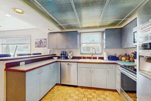 A modern kitchen with grey cabinets, a stainless steel dishwasher, and a built-in oven.