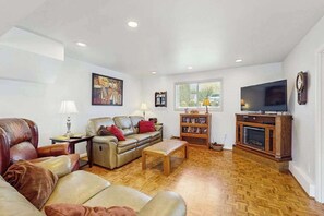 Ein Wohnzimmer mit einer Couch, einem Couchtisch, einem Fernseher und einem Kamin.