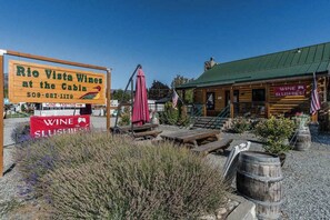 Ein rustikales Blockhaus mit einem Schild für Rio Vista Wines, Sitzgelegenheiten im Freien und einer amerikanischen Flagge.
