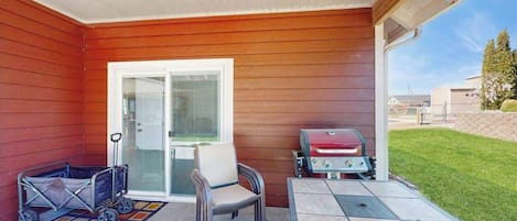 A covered patio with a grill, a stroller, and a table.