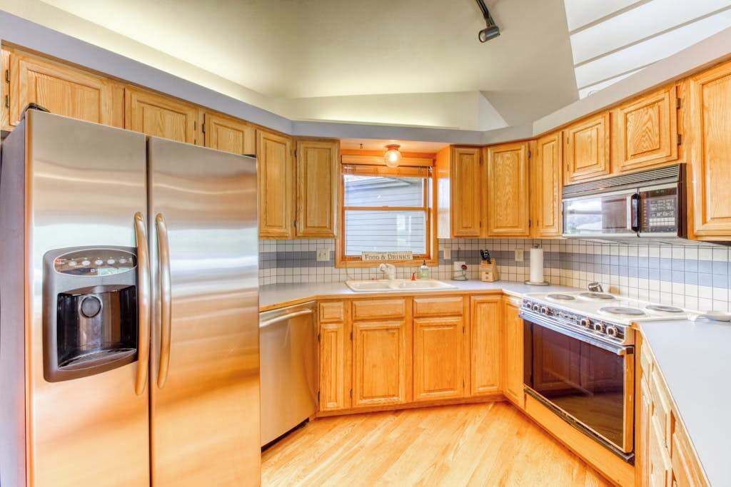 A kitchen with wooden cabinets, a stainless steel refrigerator, a microwave, and a stove.