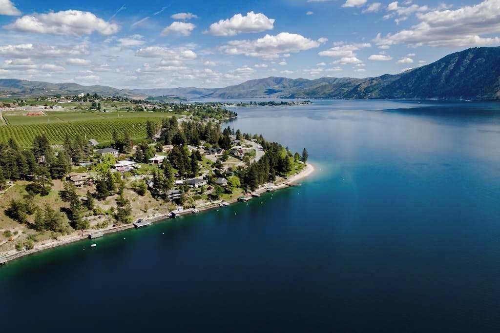 A coastal town with a marina, houses, and a mountain backdrop.