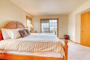 A bedroom with a large bed, a nightstand, a lamp, a window, and a door. - 3BR Lakeview - Pool - Dock - Deck (Manson)
