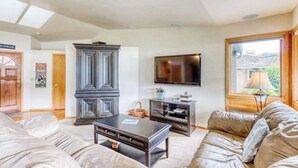 Ein Wohnzimmer mit einer Couch, einem Couchtisch, einem Fernseher und einem Schrank.