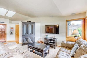 Ein Wohnzimmer mit einer Couch, einem Couchtisch, einem Fernseher und einem Schrank.