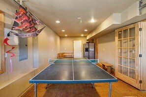 A ping pong table in a room with a wooden cabinet and a door with glass panels. - Lovely 3BR Lakeview - Deck - Ping Pong - W&D (Manson)