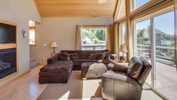 A spacious living room with a large sectional sofa, a fireplace, and a balcony with a view. - Lovely 3BR Lakeview - Deck - Ping Pong - W&D (Manson)
