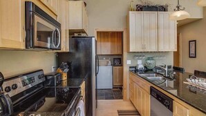 A kitchen with a stove, microwave, refrigerator, and wooden cabinets. - Lovely 3BR Lakeview - Deck - Ping Pong - W&D (Manson)