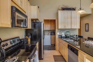 A kitchen with a stove, microwave, refrigerator, and wooden cabinets. - Lovely 3BR Lakeview - Deck - Ping Pong - W&D (Manson)
