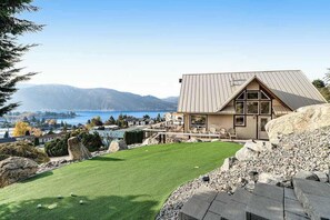 A modern house with a sloped roof, large windows, and a view of a lake and mountains. - Lovely 3BR Lakeview - Deck - Ping Pong - W&D (Manson)