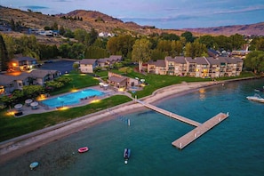 A hotel with a swimming pool, a dock, and a view of the water.