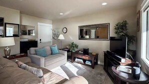 A living room with a sofa, a coffee table, a television, and a mirror. - 1BR condo with pool, hot tub & great location (Chelan)