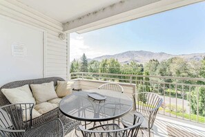 A balcony with a wicker sofa, a round table, and chairs. - Bright 2BR Lakeview - Deck - Pool - (Chelan)