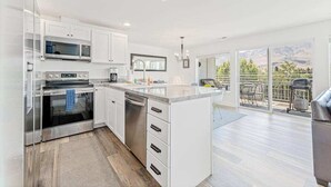 A modern kitchen with white cabinetry, stainless steel appliances, and a large island. - Bright 2BR Lakeview - Deck - Pool - (Chelan)