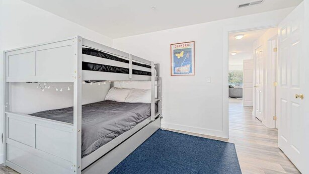 A bunk bed room with a blue carpet, white walls, and a framed picture on the wall. - Bright 2BR Lakeview - Deck - Pool - (Chelan)
