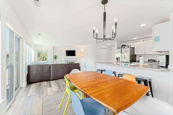 A modern kitchen with white cabinets, a central island, and a dining area with a wooden table and chairs.