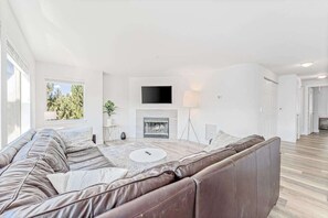 Ein modernes Wohnzimmer mit Ledersofa, Kamin, Flachbildfernseher und großem Fenster.