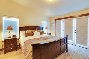 A bedroom with a large bed, two bedside tables, a nightstand, a window with blinds, and a door with a sliding closet. - Contemporary 5BR - Private Pool - Hot Tub (Manson)