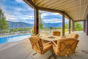 Une terrasse extérieure avec une piscine, entourée de chaises et d’une table, offrant une vue sur un paysage montagneux.