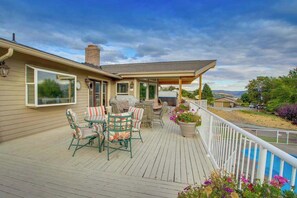 Eine überdachte Terrasse im Freien mit Essbereich, Grill und Blick auf die umliegende Landschaft.