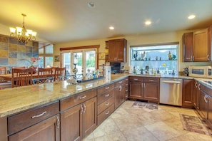 A spacious kitchen with granite countertops, wooden cabinets, and a dining area with a chandelier. - Contemporary 5BR - Private Pool - Hot Tub (Manson)