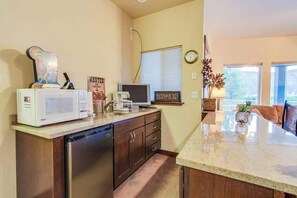 A kitchen with a microwave, toaster, and coffee maker on the counter, a clock on the wall, and a window with blinds. - Contemporary 5BR - Private Pool - Hot Tub (Manson)