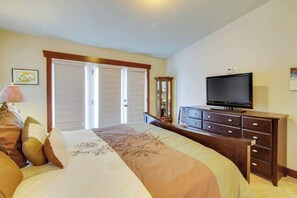 Une chambre à coucher comprenant un lit, une commode, un téléviseur et un placard avec porte coulissante.