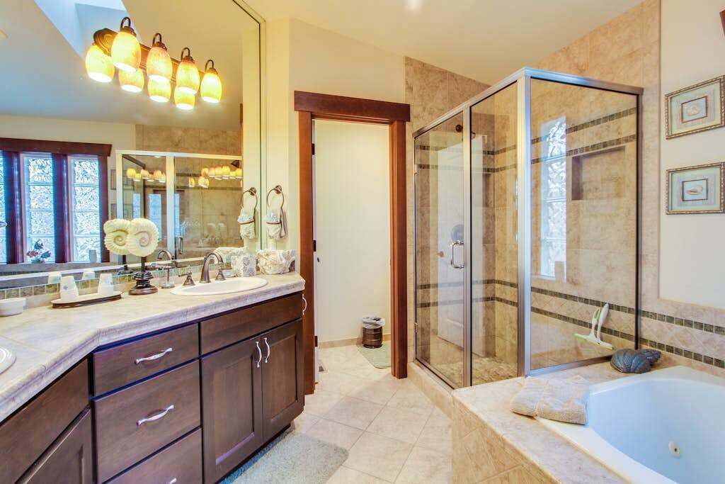 Ein modernes Badezimmer mit einer gläsernen Duschkabine, einer Badewanne und einem Waschtisch mit großem Spiegel.