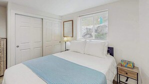 A bedroom with a bed, a nightstand, a lamp, a dresser, and a window with blinds. - Downtown 2BR - Patio - Pool - Washer/Dryer (Chelan)