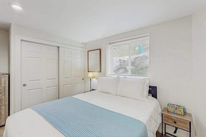 A bedroom with a bed, a nightstand, a lamp, a dresser, and a window with blinds. - Downtown 2BR - Patio - Pool - Washer/Dryer (Chelan)