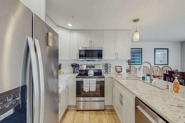 A modern kitchen with stainless steel appliances, white cabinetry, and a marble countertop. - Downtown 2BR - Patio - Pool - Washer/Dryer (Chelan)
