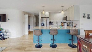 A modern kitchen with a central island, bar stools, and pendant lighting. - Downtown 2BR - Patio - Pool - Washer/Dryer (Chelan)