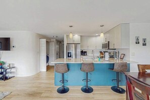 A modern kitchen with a central island, bar stools, and pendant lighting. - Downtown 2BR - Patio - Pool - Washer/Dryer (Chelan)