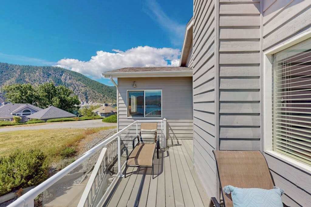 Une terrasse avec une table et des chaises, donnant sur un quartier résidentiel avec des maisons et une montagne en arrière-plan.