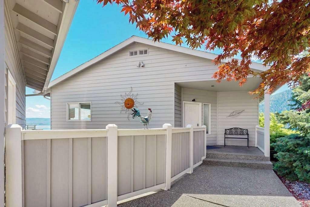 A house with a covered porch, a white fence, and a bench.