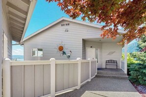 Ein Haus mit überdachter Veranda, weißem Zaun und einer Bank.