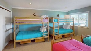 Um quarto com duas camas beliche, uma janela com persianas e uma porta.