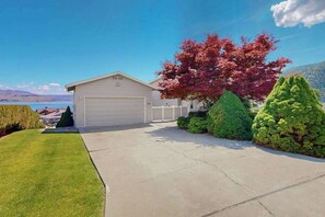 A single-story house with a garage, surrounded by well-maintained lawns and hedges, with a clear view of the sky and distant mountains. - 4BR Lakeview - Pool - Fireplace - Deck (Manson)
