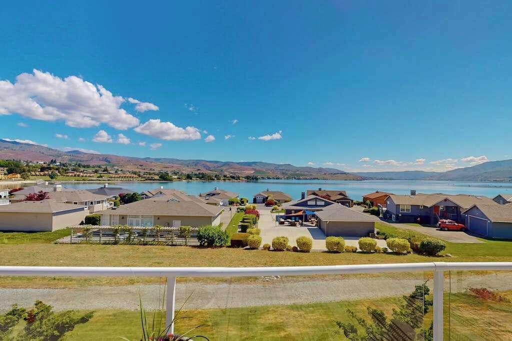 Un quartier résidentiel avec des maisons, un lac et des montagnes en arrière-plan.