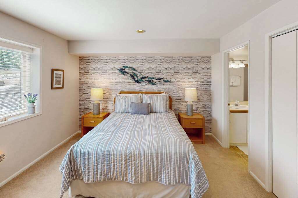 A bedroom with a bed, bedside tables, a wall-mounted artwork, and a window with blinds.