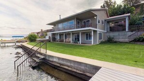 A two-story house with a balcony, a dock, and a grassy lawn. - Gorgeous 3BR Lakefront - Dock - WoodStove (Chelan)