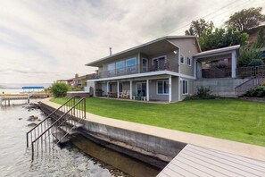 Ein zweistöckiges Haus mit Balkon, Steg und einem Rasen.