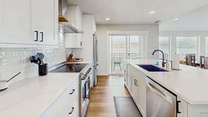 A modern kitchen with white cabinetry, stainless steel appliances, and a large island with a sink. - Gorgeous 3BR Lakefront - Dock - WoodStove (Chelan)