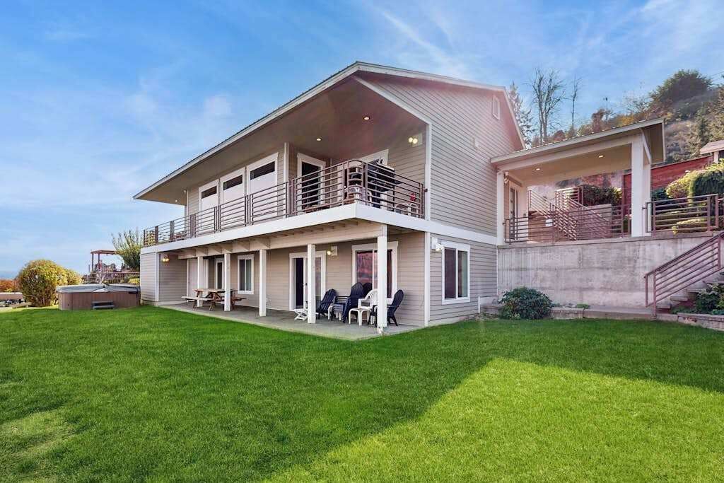 A two-story house with a covered patio and a large lawn.