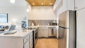 A modern kitchen with a stainless steel refrigerator, a microwave, and a dishwasher. - Comfy 1BR Lakefront - Patio - Pool - (Chelan)