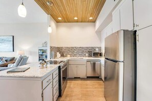 A modern kitchen with a stainless steel refrigerator, a microwave, and a dishwasher. - Comfy 1BR Lakefront - Patio - Pool - (Chelan)